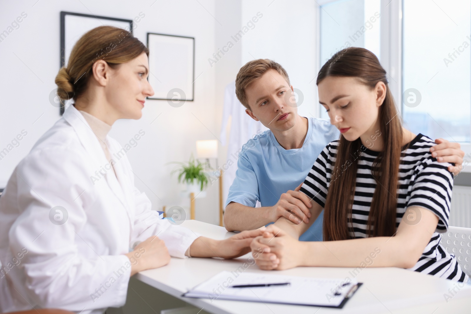 In vitro fertilization (IVF). Doctor supporting upset couple during visit in reproductive clinic Photo of In vitro fertilization (IVF). Doctor supporting upset couple during visit in reproductive clinic