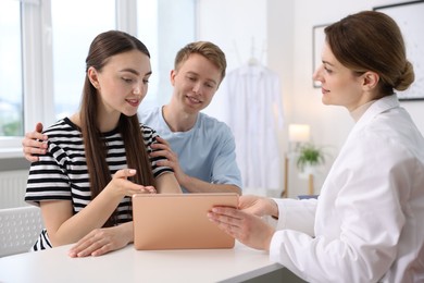 Photo of In vitro fertilization (IVF). Doctor showing couple good results on tablet in reproductive clinic