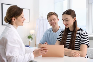 Photo of In vitro fertilization (IVF). Doctor showing couple good results on tablet in reproductive clinic