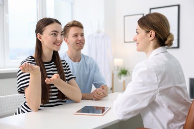 Photo of In vitro fertilization (IVF). Happy couple having appointment with doctor in reproductive clinic