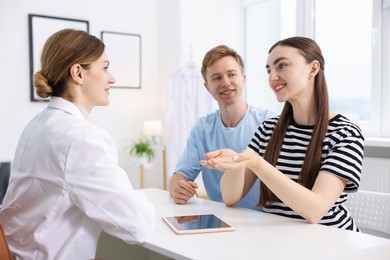 Photo of In vitro fertilization (IVF). Happy couple having appointment with doctor in reproductive clinic
