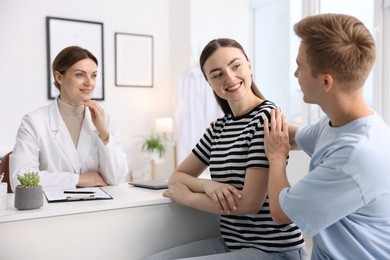 Photo of In vitro fertilization (IVF). Happy couple having appointment with doctor in reproductive clinic
