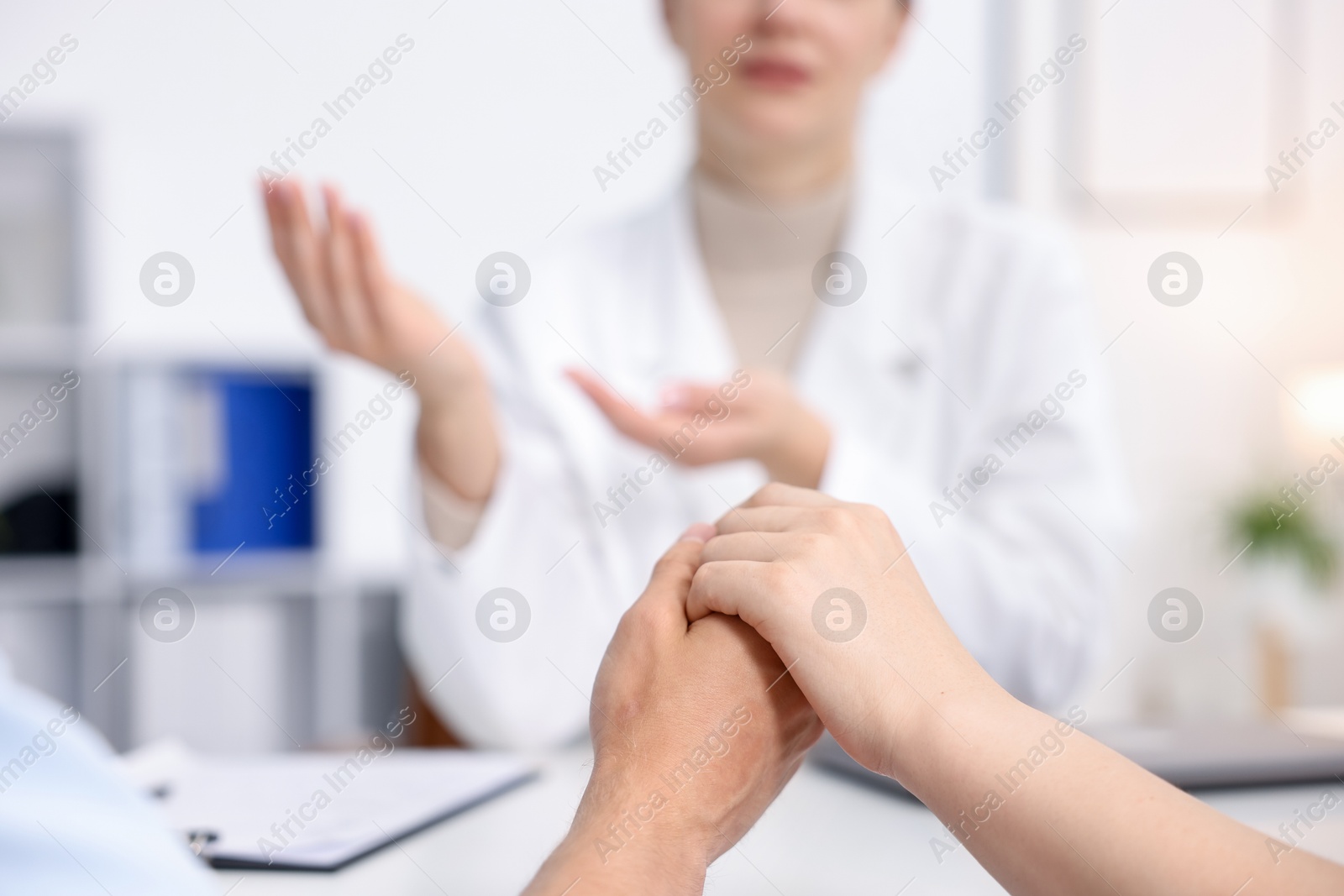Photo of In vitro fertilization (IVF). Couple holding hands during appointment with doctor in reproductive clinic, closeup