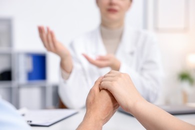 Photo of In vitro fertilization (IVF). Couple holding hands during appointment with doctor in reproductive clinic, closeup