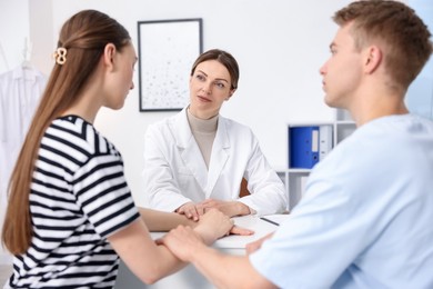 Photo of In vitro fertilization (IVF). Doctor encouraging couple during visit in reproductive clinic