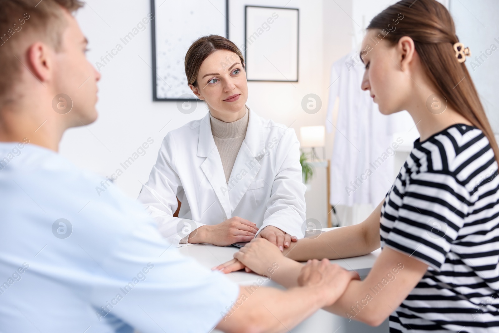 In vitro fertilization (IVF). Doctor encouraging couple during visit in reproductive clinic Photo of In vitro fertilization (IVF). Doctor encouraging couple during visit in reproductive clinic