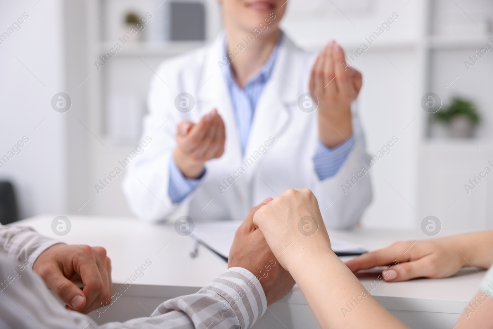 Photo of In vitro fertilization (IVF). Couple holding hands during appointment with doctor in reproductive clinic, closeup