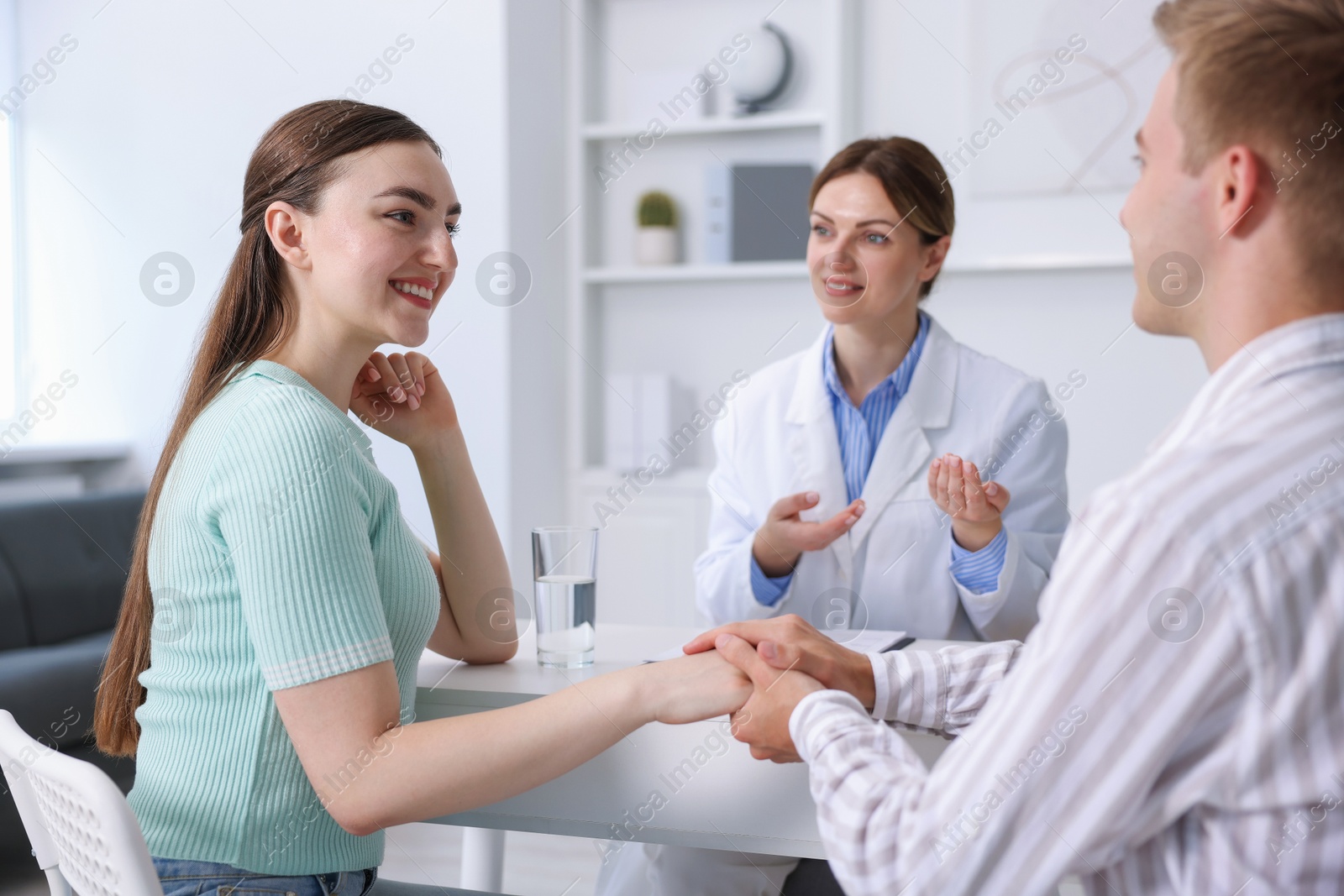 Photo of In vitro fertilization (IVF). Couple holding hands during appointment with doctor in reproductive clinic