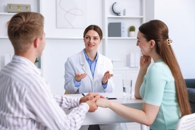 Photo of In vitro fertilization (IVF). Couple holding hands during appointment with doctor in reproductive clinic
