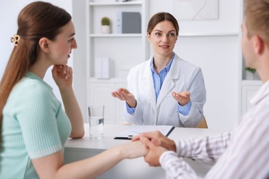 Photo of In vitro fertilization (IVF). Couple holding hands during appointment with doctor in reproductive clinic