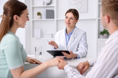 Photo of In vitro fertilization (IVF). Couple holding hands during appointment with doctor in reproductive clinic