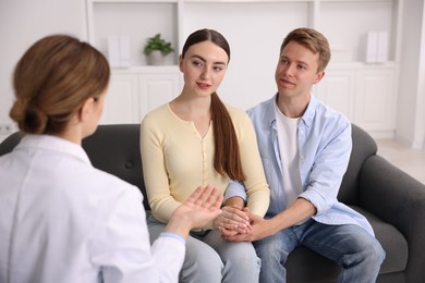 Photo of In vitro fertilization (IVF). Couple holding hands during appointment with doctor in reproductive clinic