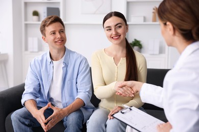Photo of In vitro fertilization (IVF). Doctor shaking hands with couple in reproductive clinic