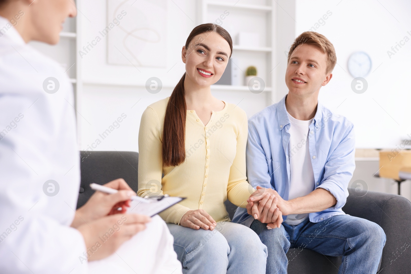 Photo of In vitro fertilization (IVF). Couple holding hands during appointment with doctor in reproductive clinic