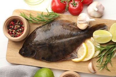 Photo of Fresh raw flounder fish and ingredients on white wooden table, flat lay. Seafood