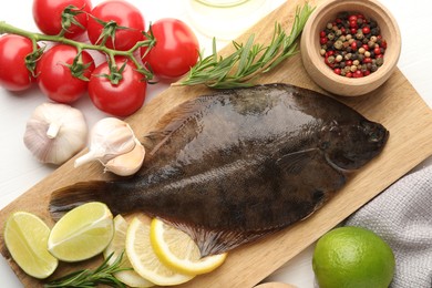 Photo of Fresh raw flounder fish and ingredients on white wooden table, flat lay. Seafood