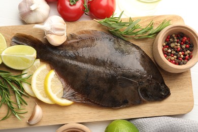Photo of Fresh raw flounder fish and ingredients on white wooden table, flat lay. Seafood