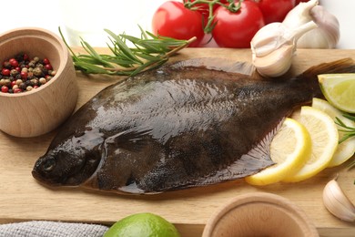 Photo of Fresh raw flounder fish and ingredients on white table, above view. Seafood