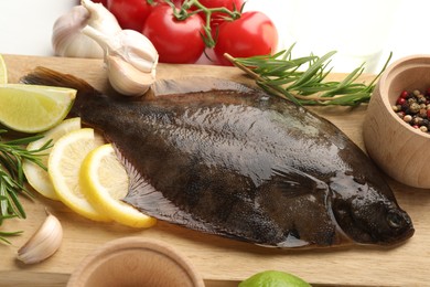 Photo of Fresh raw flounder fish and ingredients on white table, above view. Seafood