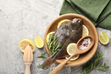 Photo of Fresh raw flounder fish, spices and wooden juicer on grey table, flat lay. Seafood