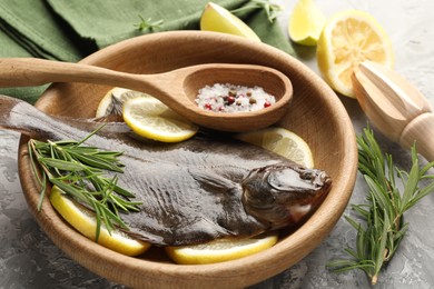 Photo of Fresh raw flounder fish, spices and wooden juicer on grey table, closeup. Seafood
