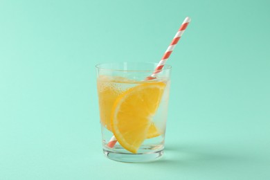 Photo of Sparkling water with orange slices in glass on turquoise background