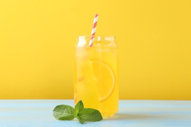 Photo of Refreshing soda water with orange slice in glass and mint on light blue wooden table
