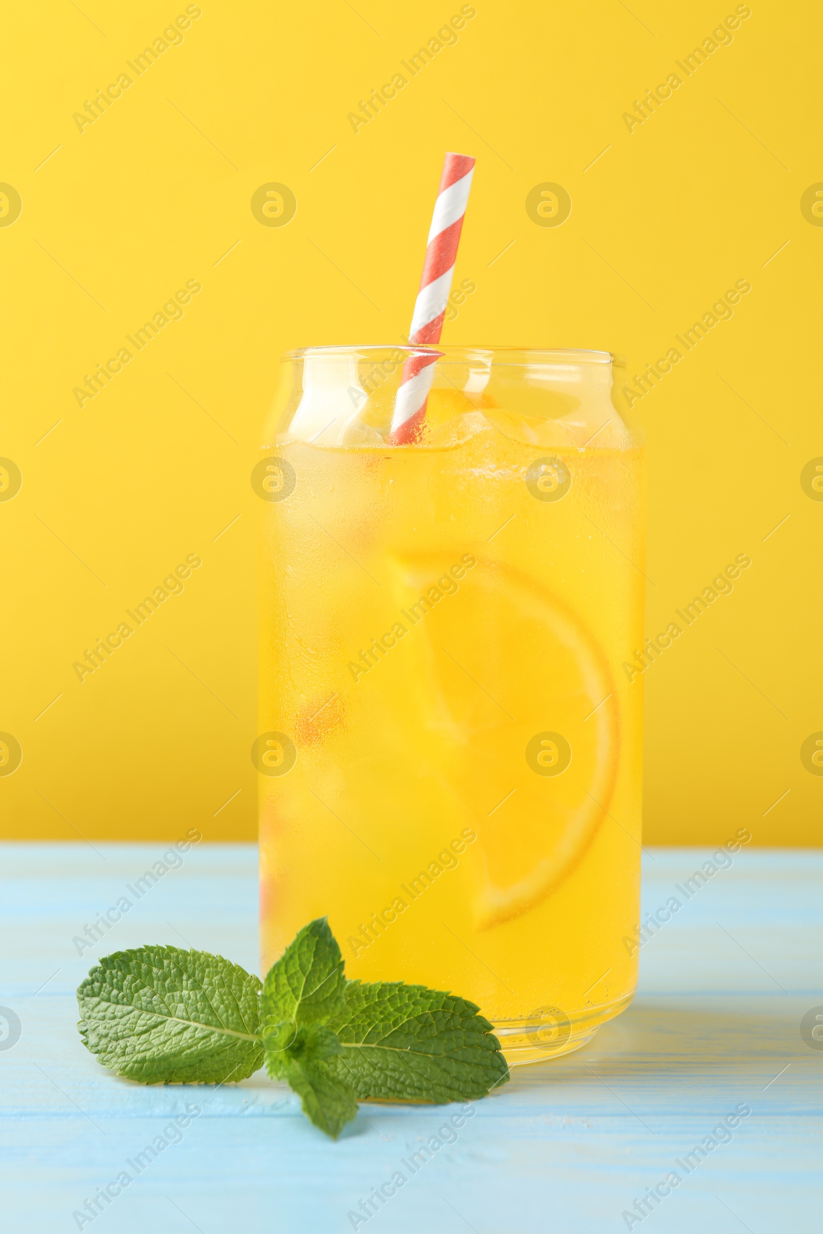 Photo of Refreshing soda water with orange slice in glass and mint on light blue wooden table, closeup