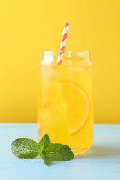 Photo of Refreshing soda water with orange slice in glass and mint on light blue wooden table, closeup