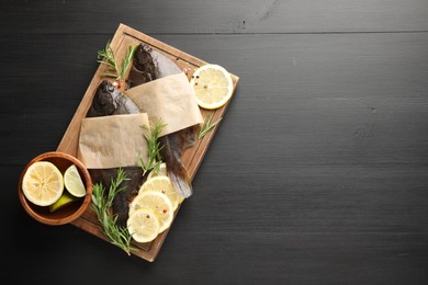 Photo of Seafood. Fresh raw flounder fish and spices on black wooden table, top view. Space for text