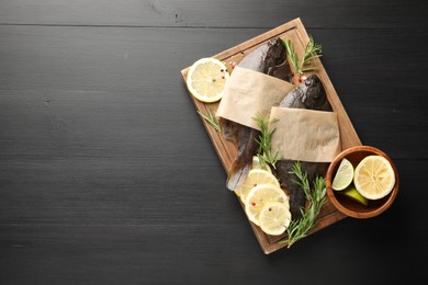 Photo of Seafood. Fresh raw flounder fish and spices on black wooden table, top view. Space for text