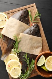 Photo of Fresh raw flounder fish and spices on black wooden table, top view. Seafood