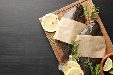 Photo of Seafood. Fresh raw flounder fish and spices on black wooden table, top view. Space for text