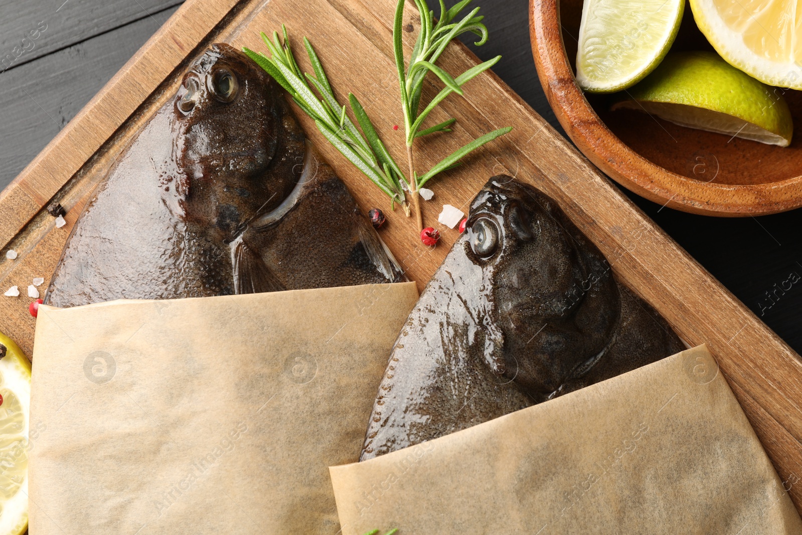 Photo of Fresh raw flounder fish and spices on black wooden table, top view. Seafood