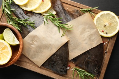 Photo of Fresh raw flounder fish and spices on black wooden table, top view. Seafood