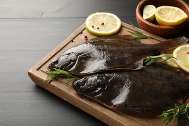 Photo of Fresh raw flounder fish and spices on black wooden table, closeup. Seafood