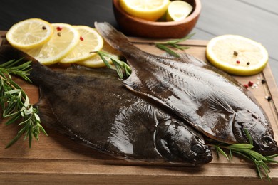 Photo of Fresh raw flounder fish and spices on black wooden table, closeup. Seafood