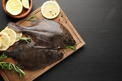 Photo of Seafood. Fresh raw flounder fish and spices on black wooden table, flat lay. Space for text