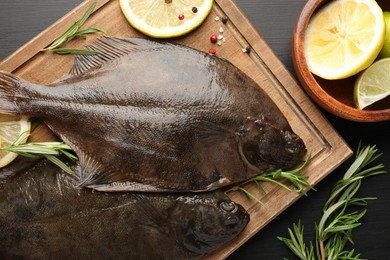 Photo of Fresh raw flounder fish and spices on black wooden table, flat lay. Seafood