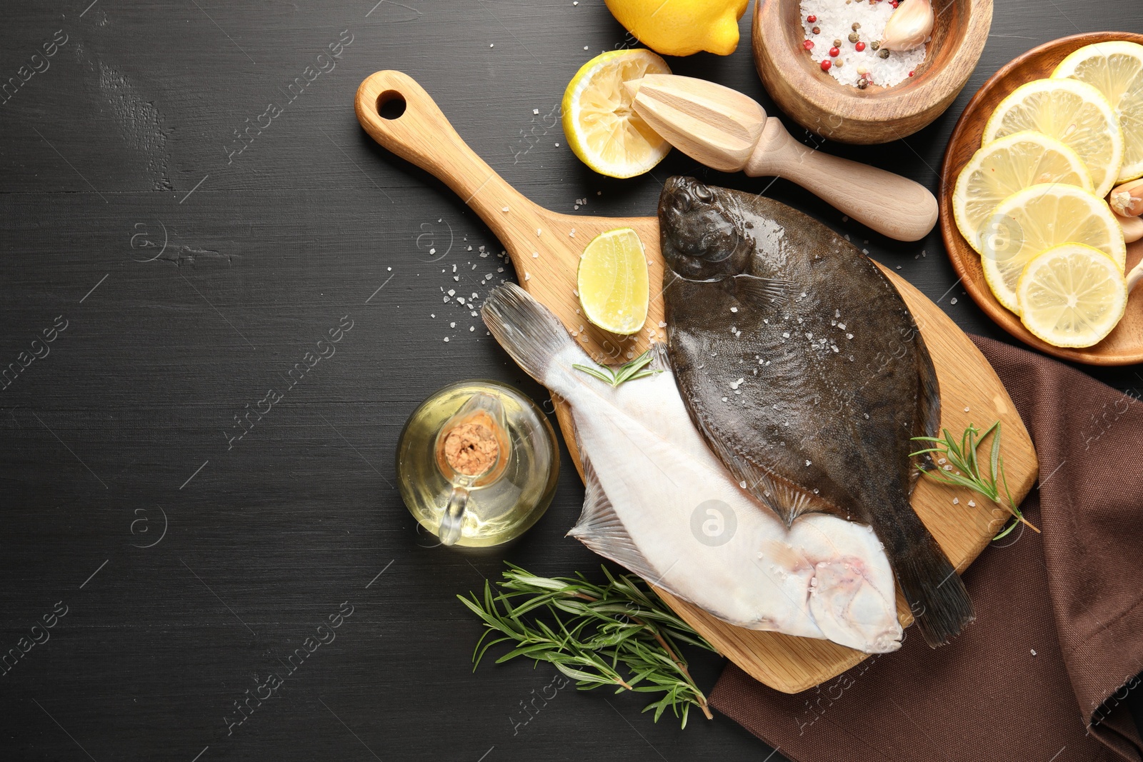 Seafood. Fresh raw flounder fish, spices and juicer on black wooden table, flat lay. Space for text Photo of Seafood. Fresh raw flounder fish, spices and juicer on black wooden table, flat lay. Space for text