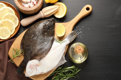 Photo of Seafood. Fresh raw flounder fish, spices and juicer on black wooden table, flat lay. Space for text