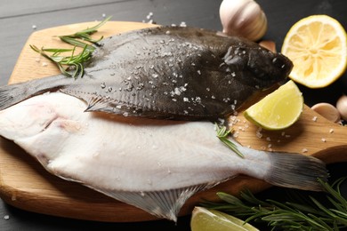 Photo of Fresh raw flounder fish and spices on black wooden table, closeup. Seafood