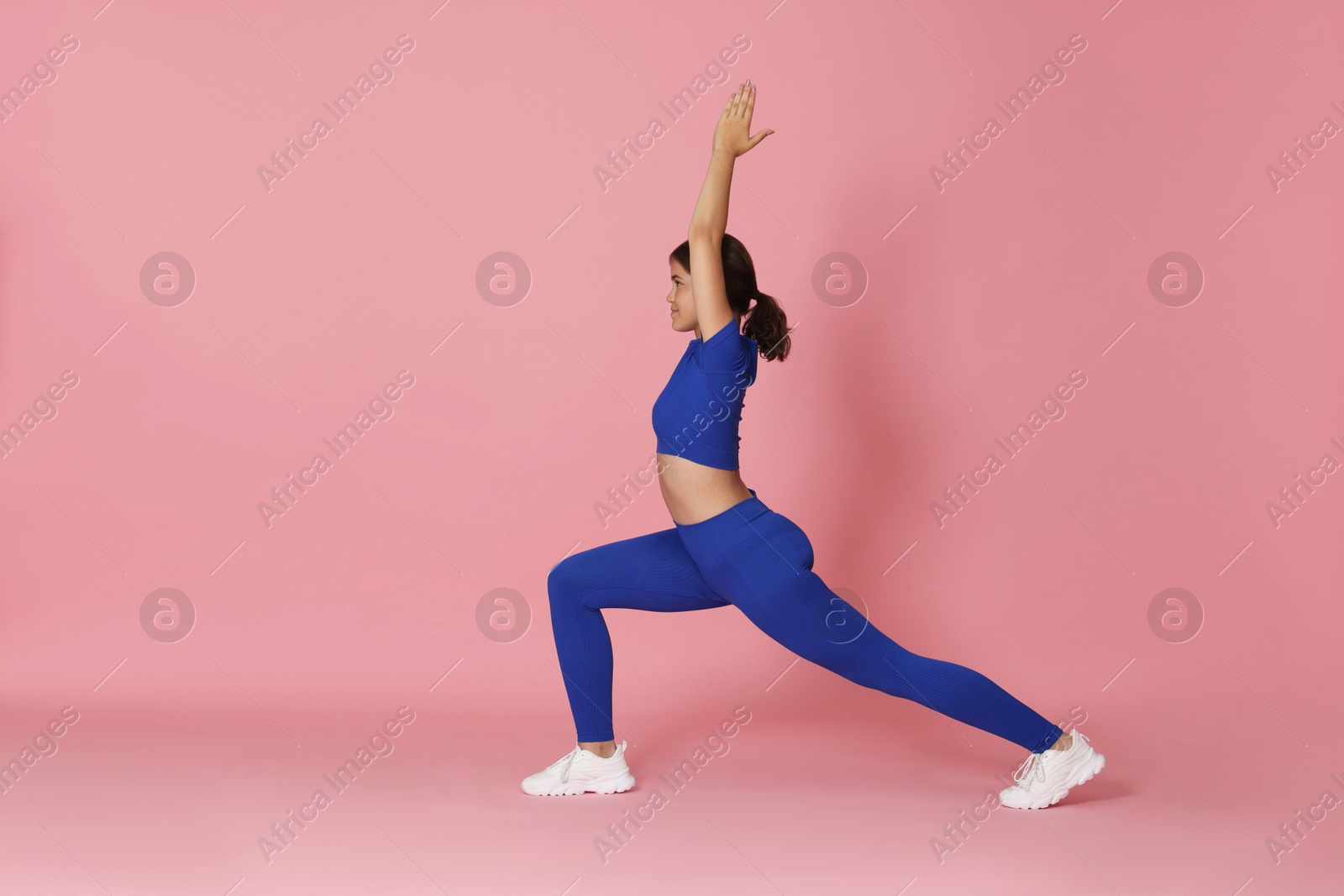 Teenage girl in sportswear stretching on pink background, space for text Photo of Teenage girl in sportswear stretching on pink background, space for text