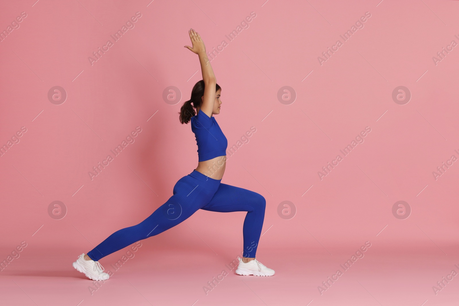 Teenage girl in sportswear stretching on pink background, space for text Photo of Teenage girl in sportswear stretching on pink background, space for text