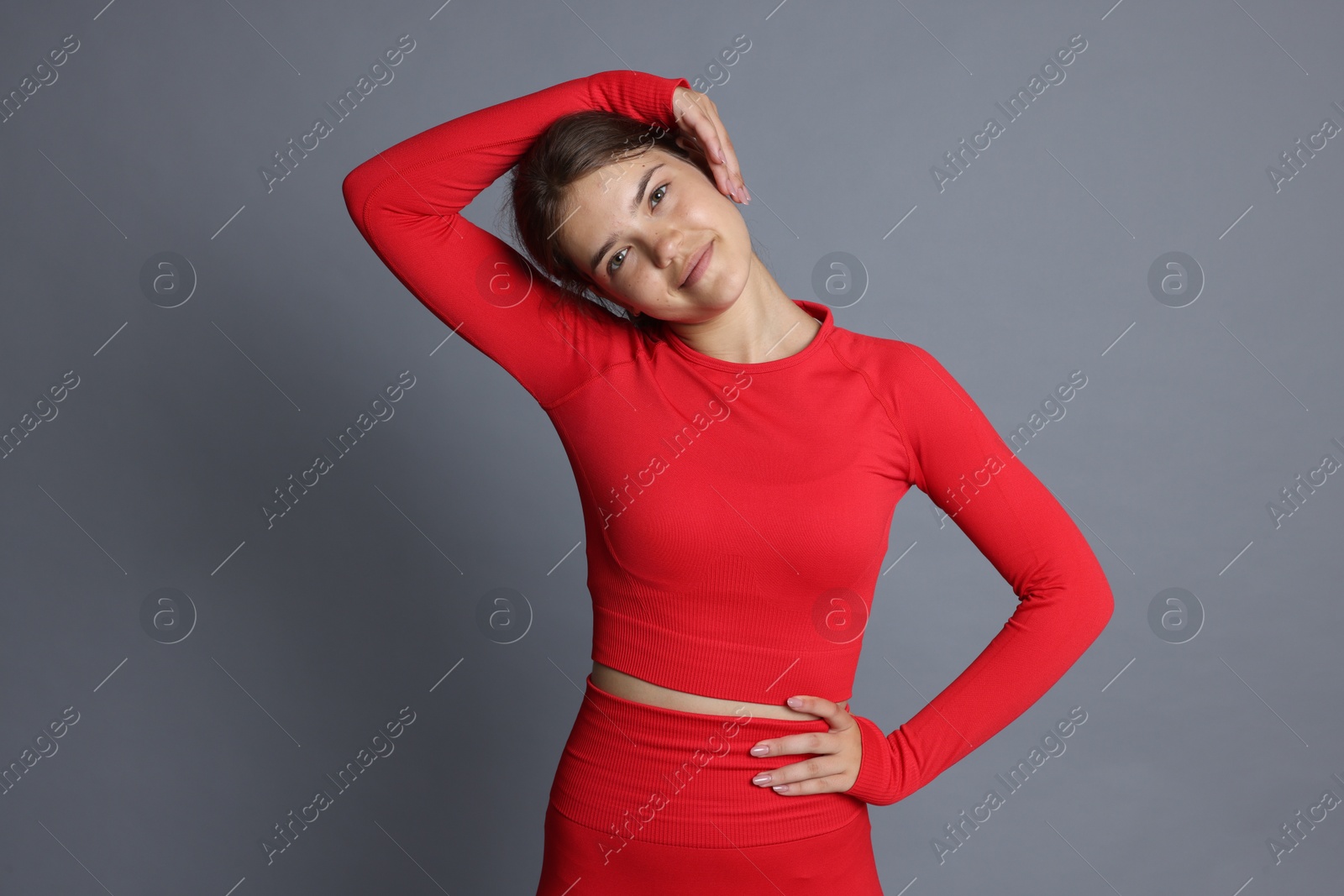 Teenage girl in sportswear stretching on grey background Photo of Teenage girl in sportswear stretching on grey background