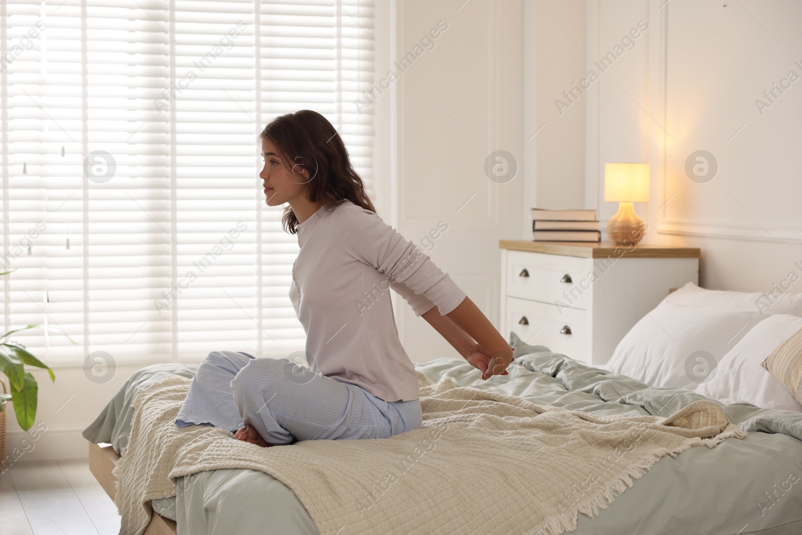 Teenage girl stretching on bed at home Photo of Teenage girl stretching on bed at home