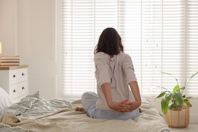 Photo of Teenage girl stretching on bed at home, back view. Space for text