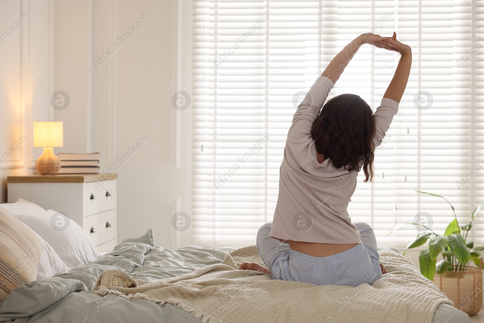 Teenage girl stretching on bed at home, back view. Space for text Photo of Teenage girl stretching on bed at home, back view. Space for text