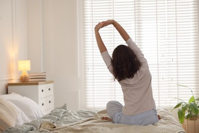 Photo of Teenage girl stretching on bed at home, back view. Space for text