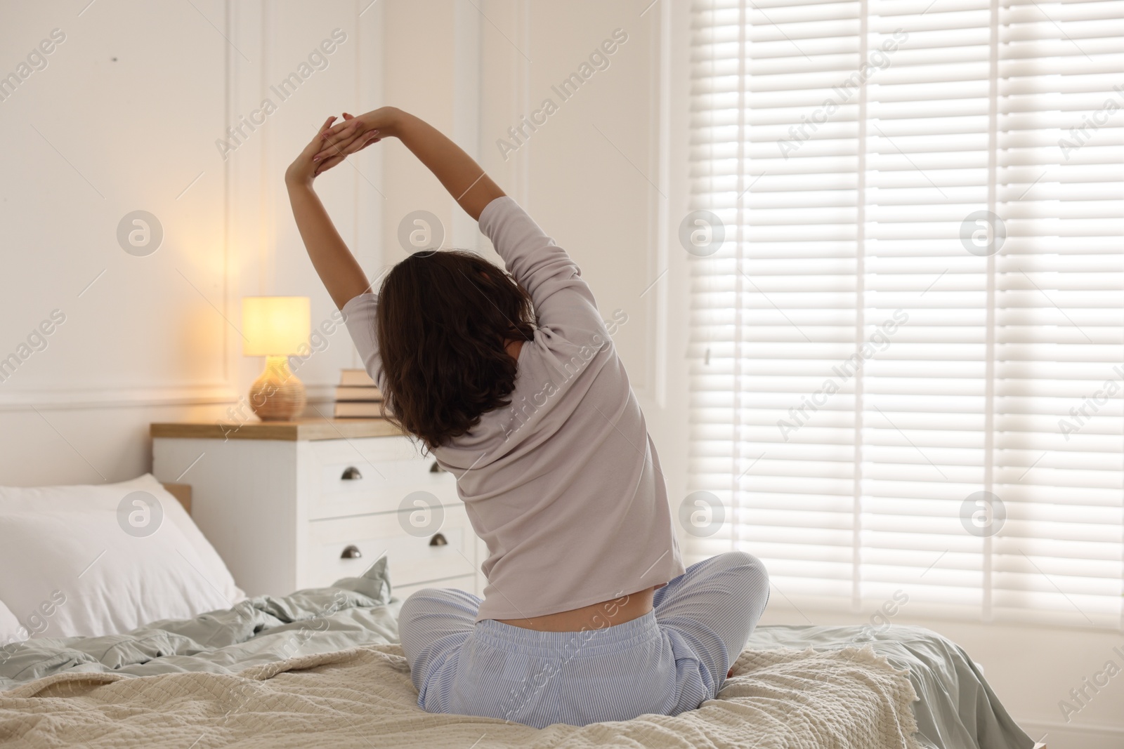 Teenage girl stretching on bed at home, back view Photo of Teenage girl stretching on bed at home, back view